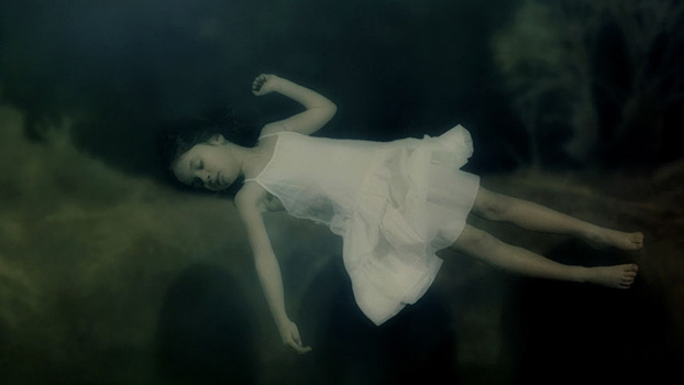 A child with a white dress sleeping underwater